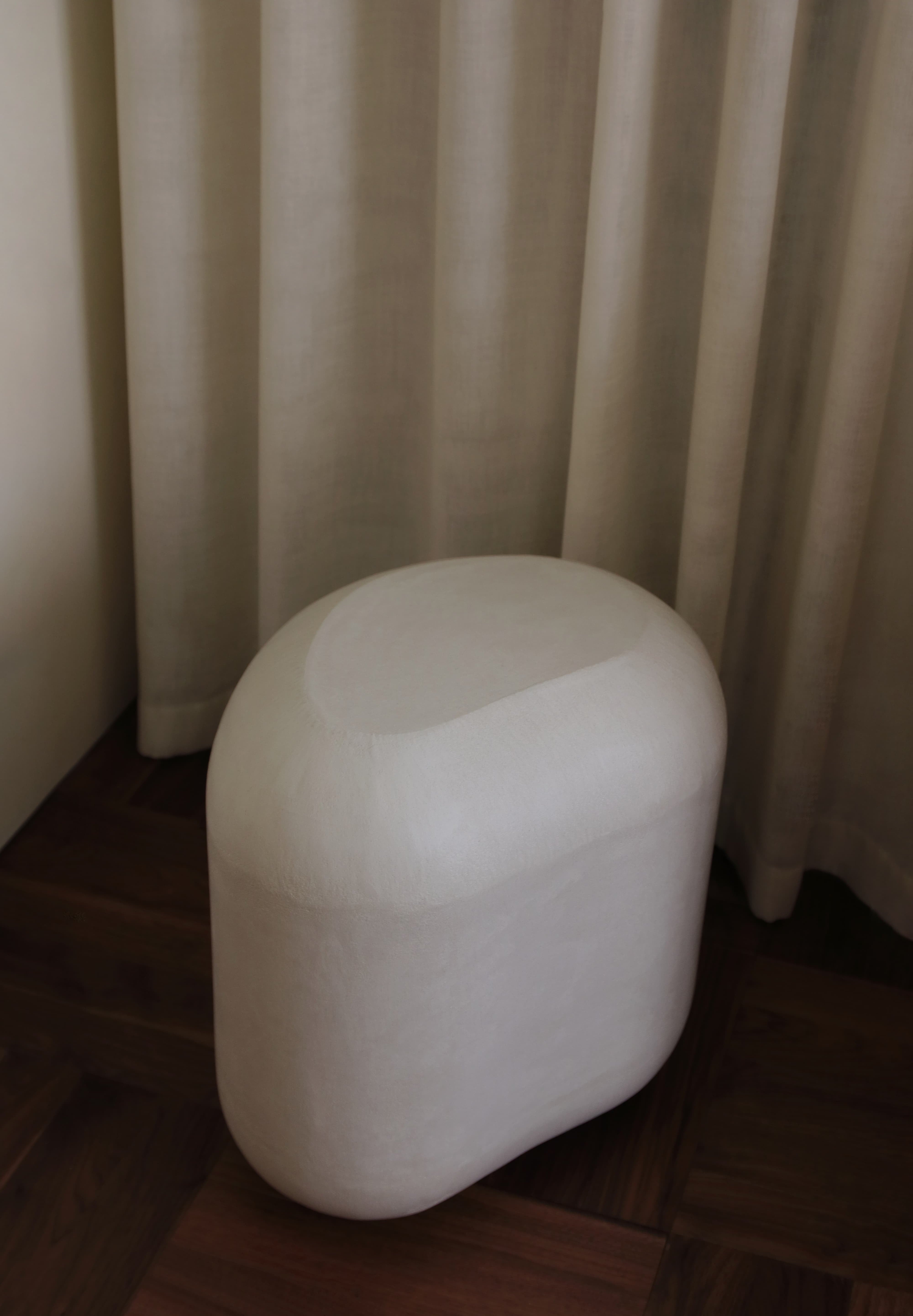 Sculptural MAIE side table in Clay Crème with a subtly grained surface and rounded, asymmetrical form.