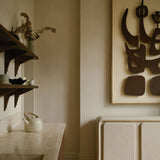 MAIE Clay Duvet sideboard beneath abstract wall art in a warm neutral interior with timber flooring and open shelving.