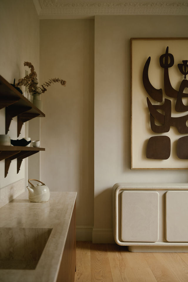 MAIE Clay Duvet sideboard beneath abstract wall art in a warm neutral interior with timber flooring and open shelving.