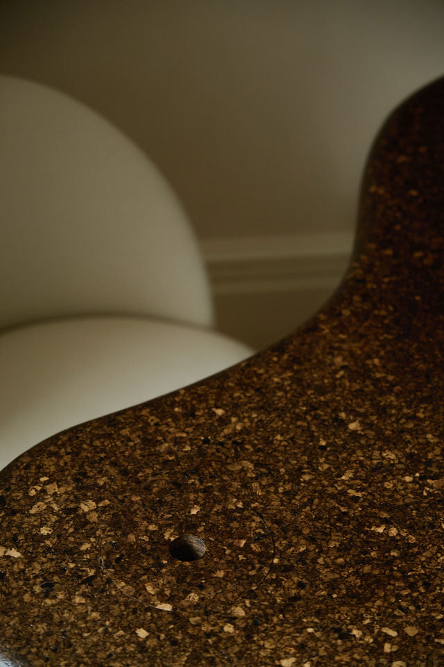 Sculptural MAIE desk in Espresso cork with a satin finish, organically curved tabletop and cylindrical legs.