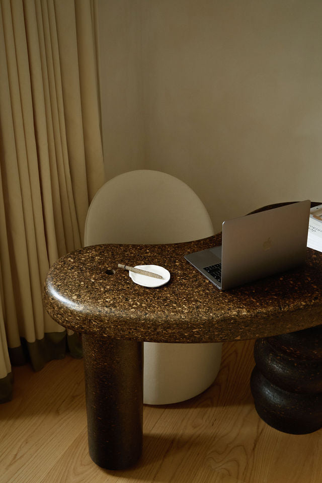 MAIE desk in tactile Espresso cork with a satin finish, styled with a laptop and cream chair in a neutral interior.