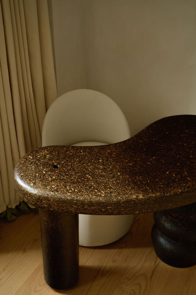 Sculptural MAIE desk in Espresso cork with a satin finish, organically curved tabletop and cylindrical legs.