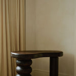 Sculptural MAIE desk in Espresso cork with a satin finish, organically curved tabletop and cylindrical legs.