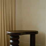 Sculptural MAIE desk in Espresso cork with a satin finish, organically curved tabletop and cylindrical legs.