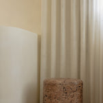 An organic-shaped cork side table or stool with a rounded form and tactile, textured surface.