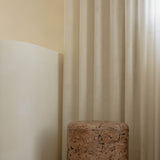 An organic-shaped cork side table or stool with a rounded form and tactile, textured surface.