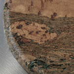 Close-up of the Marbled cork coaster showing soft green lines through warm cork grain, tactile texture and MAIE logo.