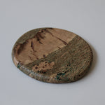 Round, organic-shaped Marbled cork coaster with soft green flowing lines, warm tan grain, a tactile textured surface and satin finish.