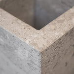 Close-up of a honed Limestone Portland Cube Holder corner, with pale stone, embedded fragments and fine surface pits.