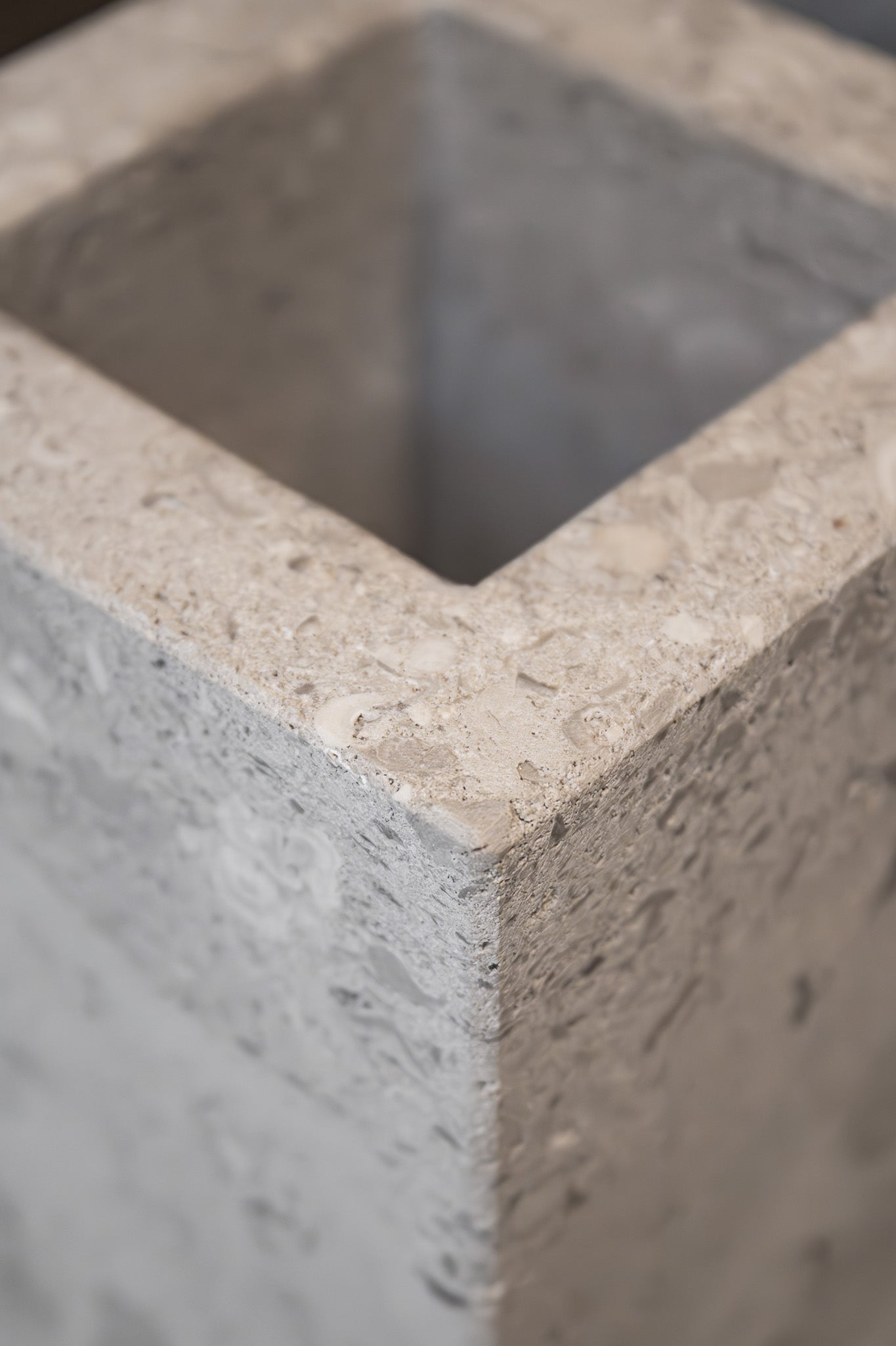 Close-up of a honed Limestone Portland Cube Holder corner, with pale stone, embedded fragments and fine surface pits.