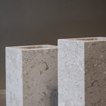 Close-up of a honed Limestone Portland Cube Holder corner, with pale stone, embedded fragments and fine surface pits.