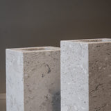 Close-up of a honed Limestone Portland Cube Holder corner, with pale stone, embedded fragments and fine surface pits.