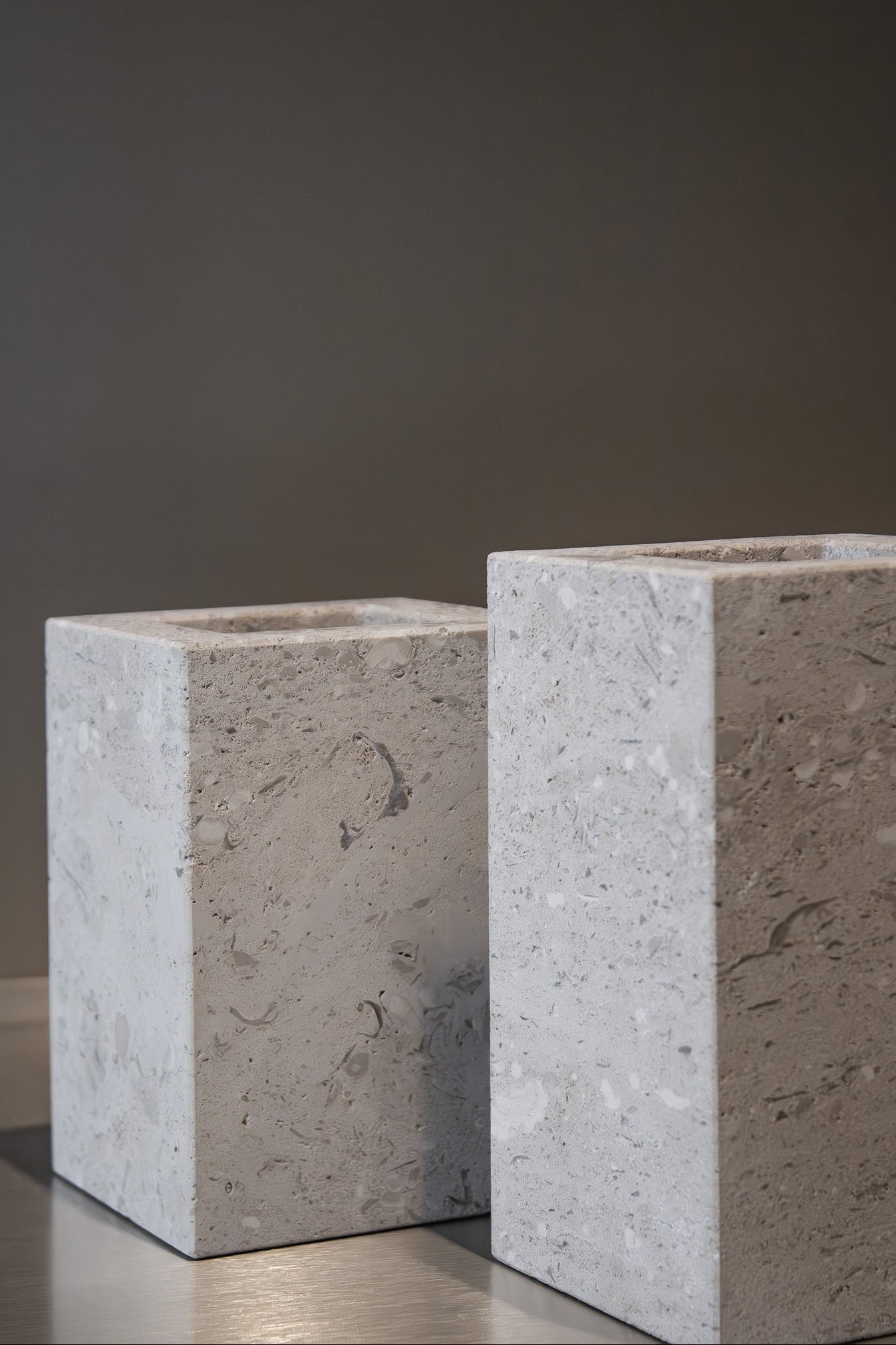 Close-up of a honed Limestone Portland Cube Holder corner, with pale stone, embedded fragments and fine surface pits.