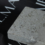 Honed Limestone Portland with a grey-beige base, scattered fossil-like fragments, fine pits and subtle tonal variation.