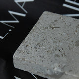 Honed Limestone Portland with a grey-beige base, scattered fossil-like fragments, fine pits and subtle tonal variation.