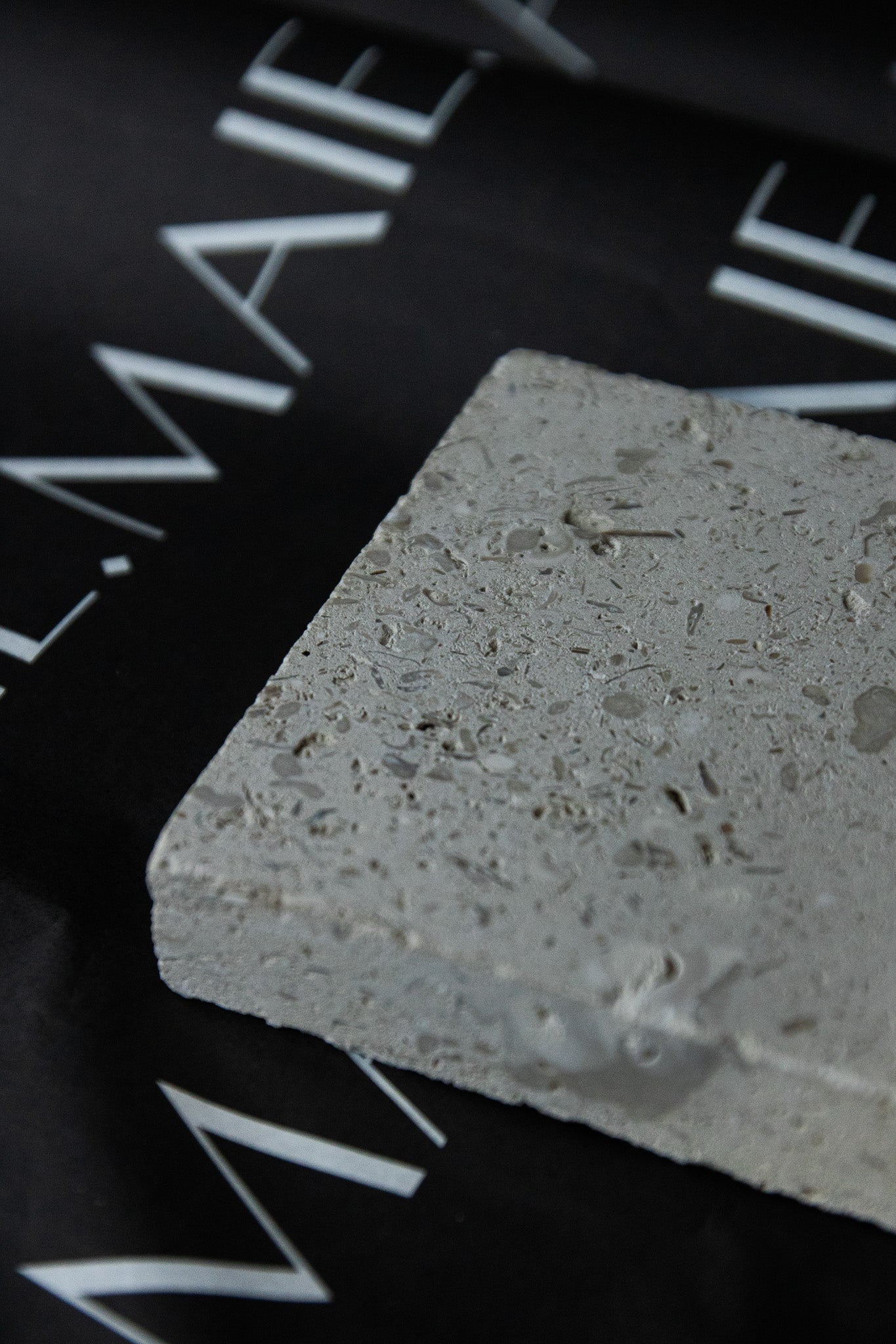 Honed Limestone Portland with a grey-beige base, scattered fossil-like fragments, fine pits and subtle tonal variation.