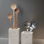 Honed Limestone Portland Cube Holders styled with wooden spoons and metal utensils against a warm grey wall.