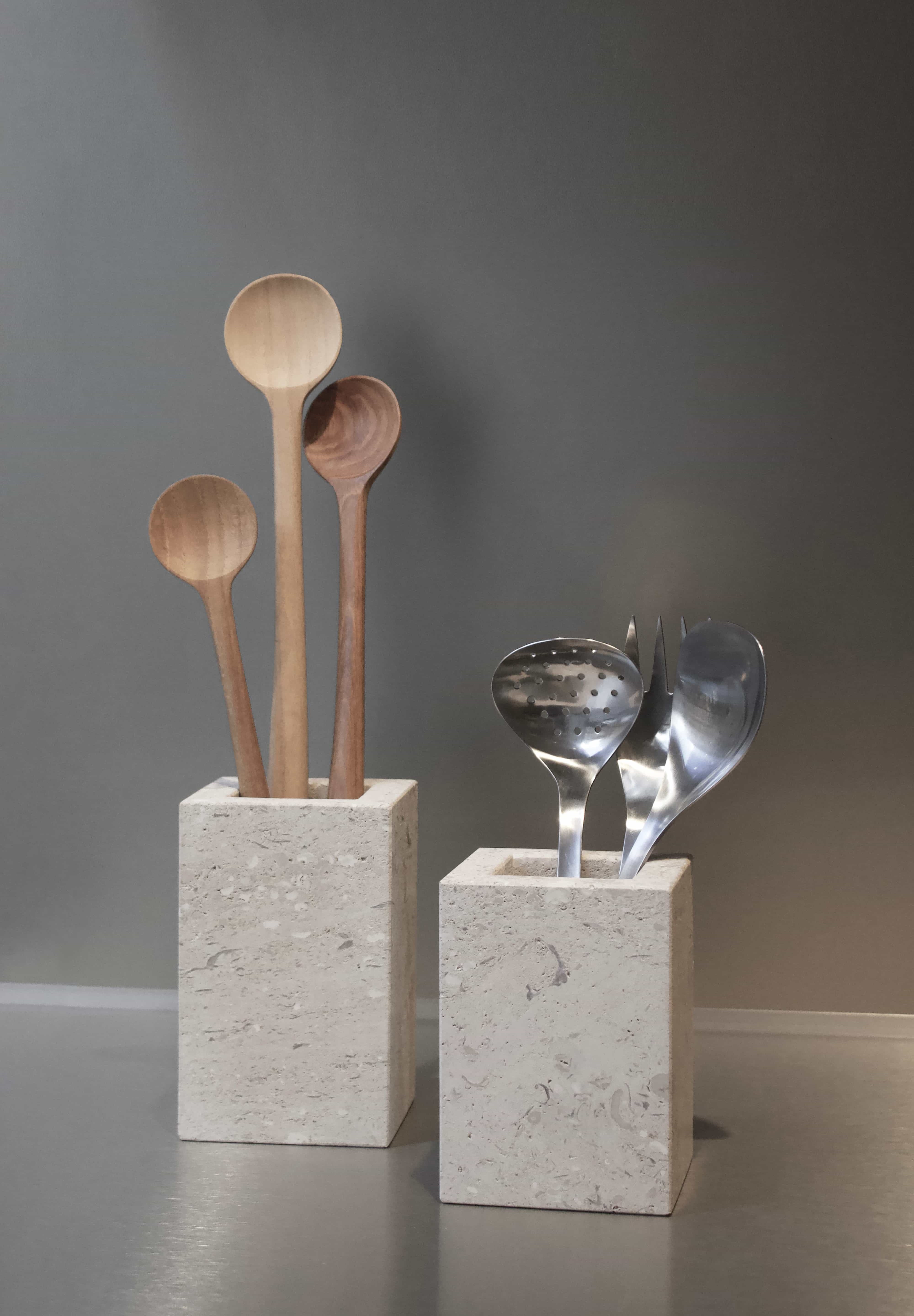 Honed Limestone Portland Cube Holders styled with wooden spoons and metal utensils against a warm grey wall.