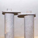 Honed Limestone Portland Side Tables with a rounded tabletop and cylindrical pedestal, in pale grey-beige stone with fine speckling.