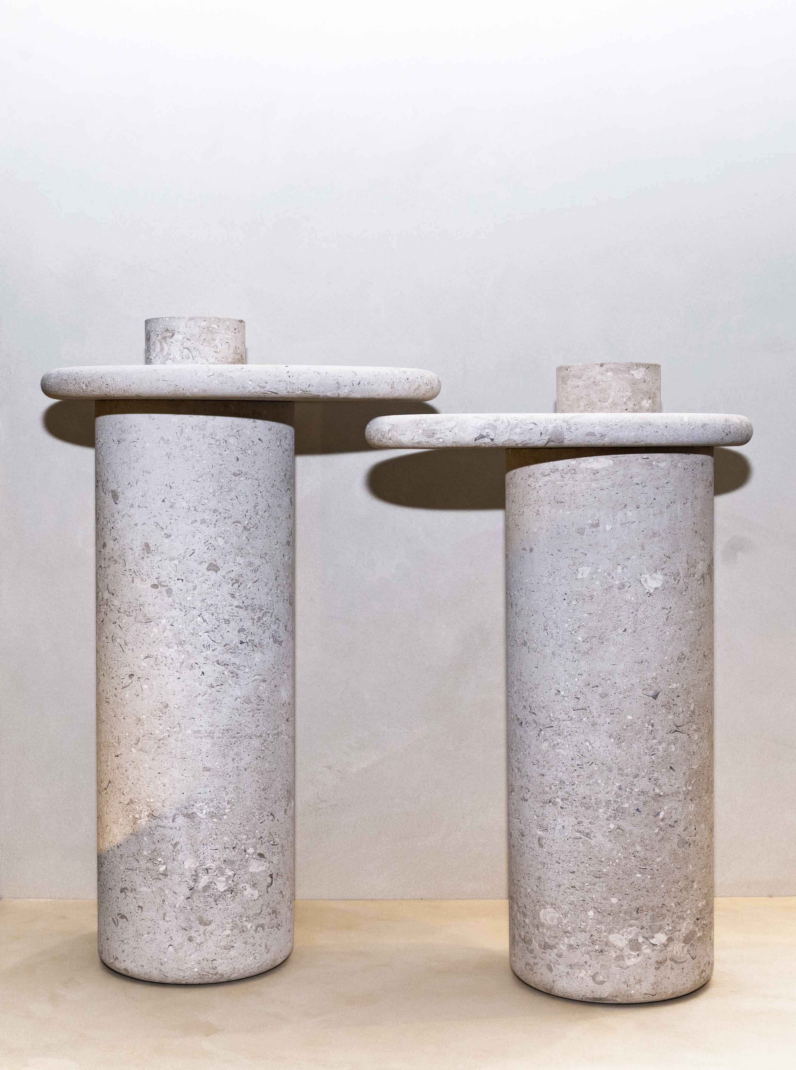 Honed Limestone Portland Side Tables with a rounded tabletop and cylindrical pedestal, in pale grey-beige stone with fine speckling.