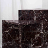 Architectural Rosso Levanto marble side tables with white veining, positioned between grey lounge chairs in a contemporary interior.