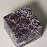 Stack of square MAIE coasters in Rosso Levanto, showing fine white veining across a rich burgundy-red surface.