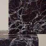Close-up of Rosso Levanto marble coasters showing fine white veining across a rich burgundy-red surface.