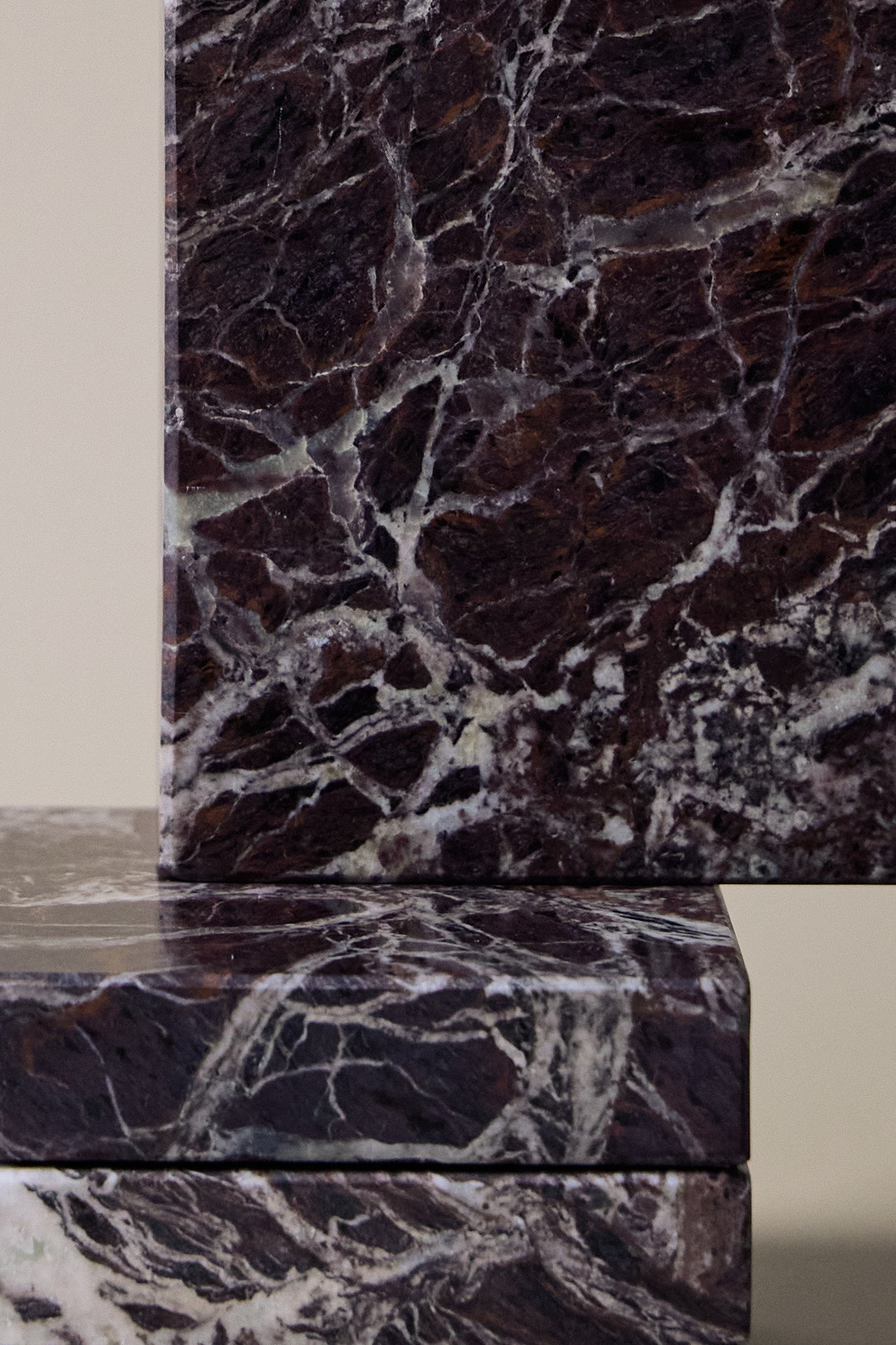 Close-up of Rosso Levanto marble coasters showing fine white veining across a rich burgundy-red surface.