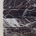 Close-up of Rosso Levanto marble coasters showing fine white veining across a rich burgundy-red surface.