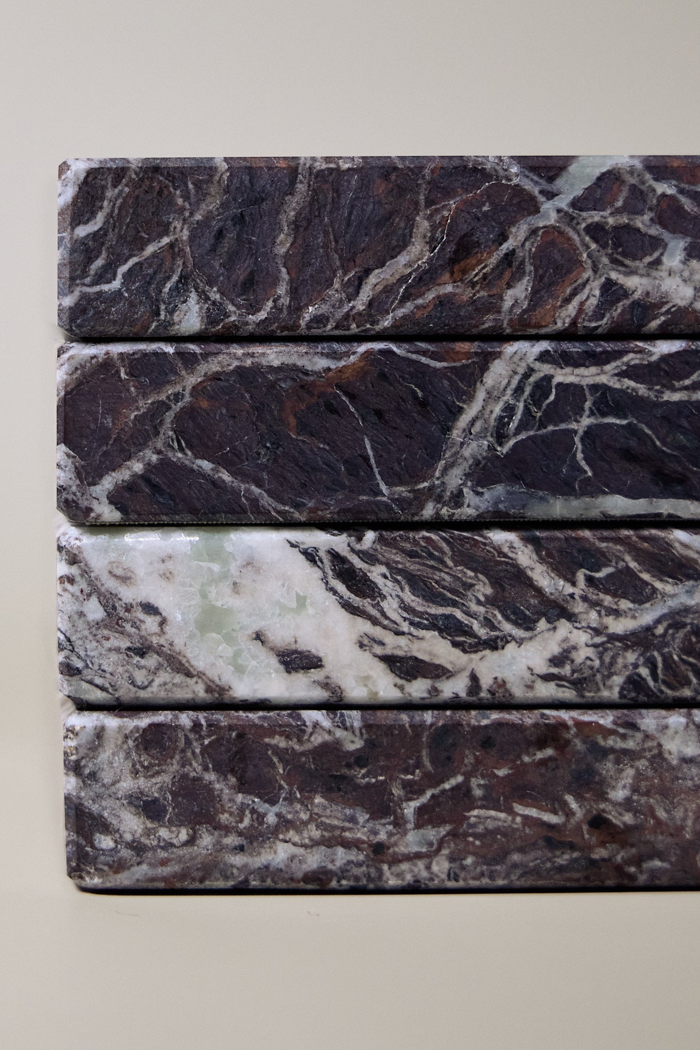Close-up of Rosso Levanto marble coasters showing fine white veining across a rich burgundy-red surface.