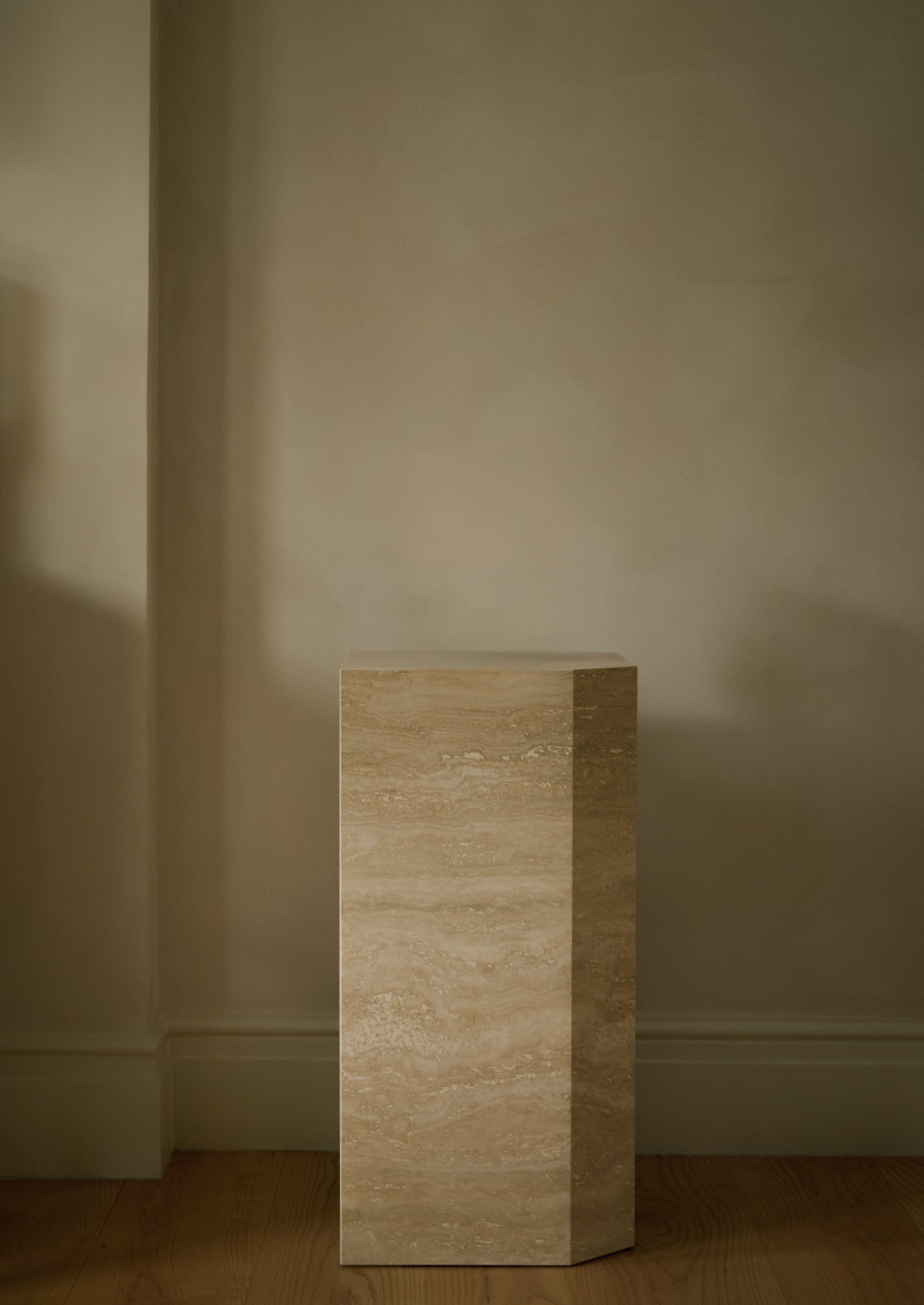 Angular Travertino Classico VC marble plinth with warm-toned veining against a natural soft interior.