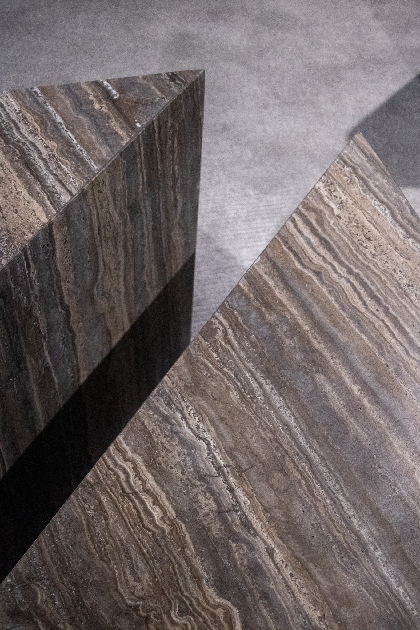 Close-up of Travertino Marrone showing natural pores, irregular veining and layered grey-brown tones along stacked stone edges.