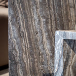 Close-up of Travertino Marrone showing natural pores, irregular veining and layered grey-brown tones along stacked stone edges.