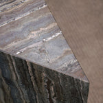 Close-up of Travertino Marrone showing natural pores, irregular veining and layered grey-brown tones along stacked stone edges.