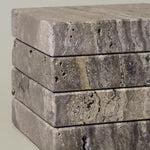 Close-up of Travertino Marrone showing natural pores, irregular veining and layered grey-brown tones along stacked stone edges.