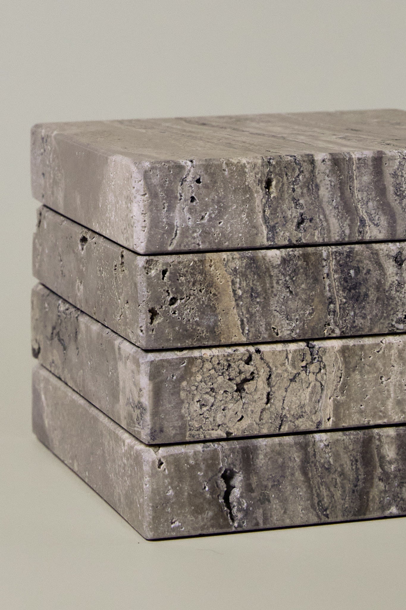 Close-up of Travertino Marrone showing natural pores, irregular veining and layered grey-brown tones along stacked stone edges.