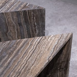 Close-up of Travertino Marrone showing natural pores, irregular veining and layered grey-brown tones along stacked stone edges.