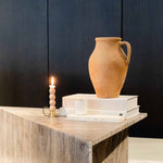 Travertino Marrone coffee table with natural linear veining, styled with a terracotta vase, books and a lit candle.
Copy alt text