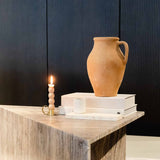 Travertino Marrone coffee table with natural linear veining, styled with a terracotta vase, books and a lit candle.
Copy alt text