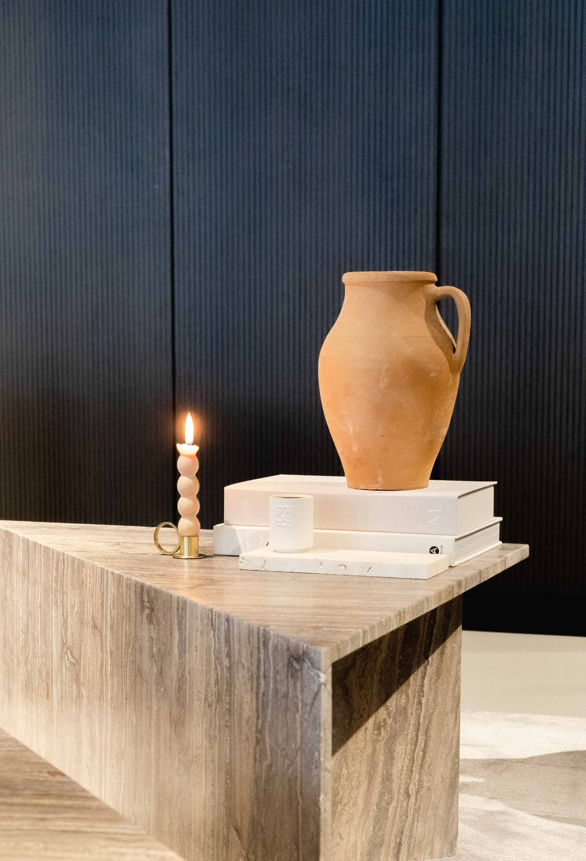Travertino Marrone coffee table with natural linear veining, styled with a terracotta vase, books and a lit candle.
Copy alt text